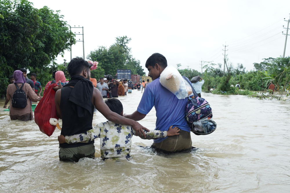 Leute laufen in der Mitte der Überschwemmung in Bangladesh